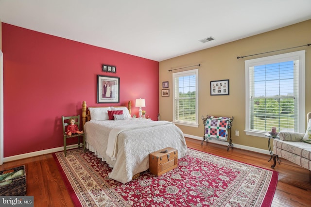 bedroom featuring multiple windows, wood finished floors, and baseboards