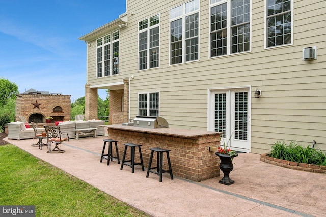 view of patio featuring exterior kitchen, a bar, and an outdoor living space with a fireplace