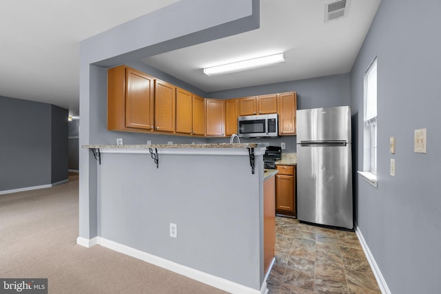 9150 Gracious End Ct Unit 104, Columbia, MD 21046 - kitchen with stainless steel appliances, baseboards, a peninsula, a breakfast bar, and light stone counters