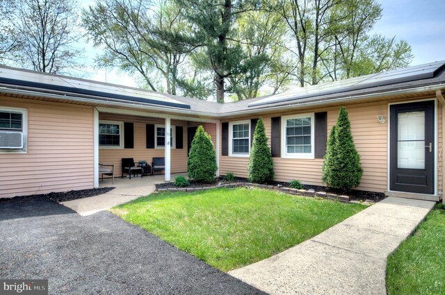 24 Edgewater Ln, Willingboro, NJ 08046 - view of exterior entry featuring a lawn, solar panels, and cooling unit