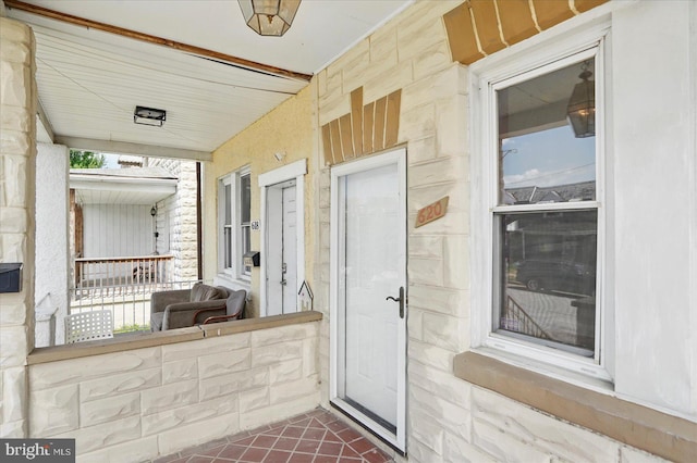 entrance to property featuring stone siding and a porch