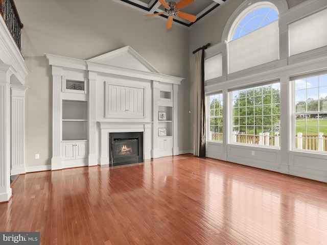 12810 Macbeth Farm Ln, Clarksville, MD 21029 - unfurnished living room featuring ceiling fan, a fireplace with flush hearth, wood finished floors, built in shelves, and a high ceiling