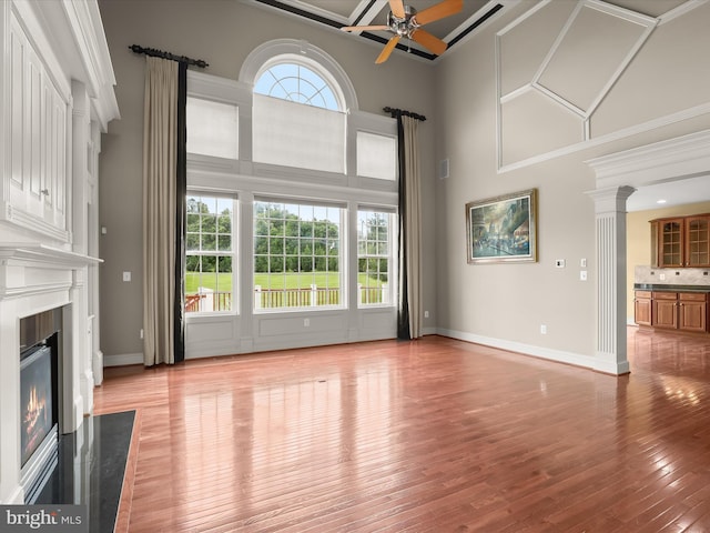 12810 Macbeth Farm Ln, Clarksville, MD 21029 - unfurnished living room with a towering ceiling, a ceiling fan, light wood-type flooring, a fireplace, and ornate columns