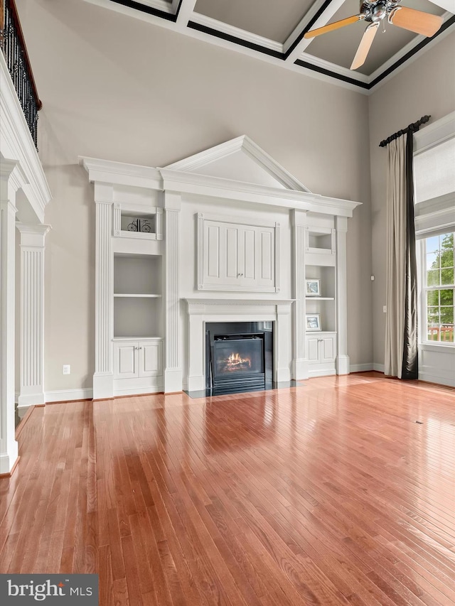 12810 Macbeth Farm Ln, Clarksville, MD 21029 - unfurnished living room featuring a glass covered fireplace, a ceiling fan, hardwood / wood-style flooring, a towering ceiling, and built in shelves