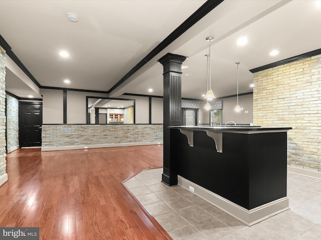 12810 Macbeth Farm Ln, Clarksville, MD 21029 - kitchen with brick wall, light wood-style flooring, a breakfast bar, crown molding, and decorative light fixtures