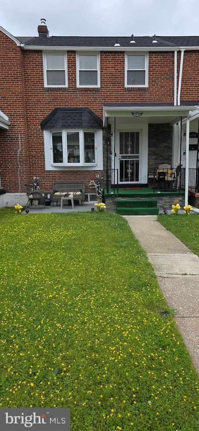 view of front facade with brick siding and a front lawn