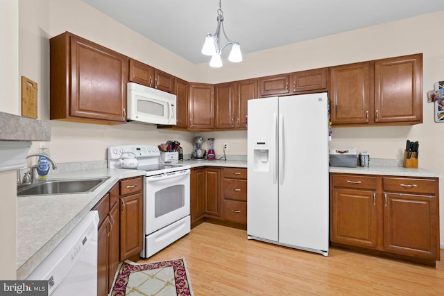 kitchen featuring white appliances, a sink, light wood-style floors, and light countertops