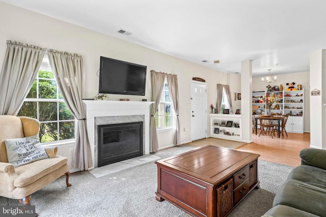 living room featuring a chandelier and a fireplace with flush hearth