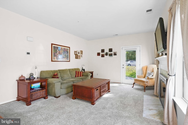 living room with light carpet, a fireplace with flush hearth, and baseboards
