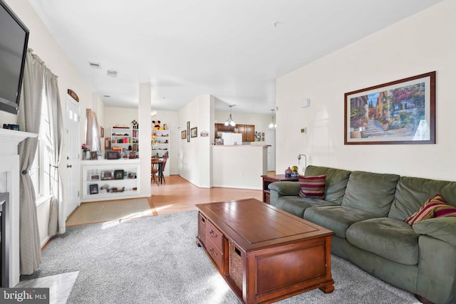 living area featuring light colored carpet and a fireplace with flush hearth