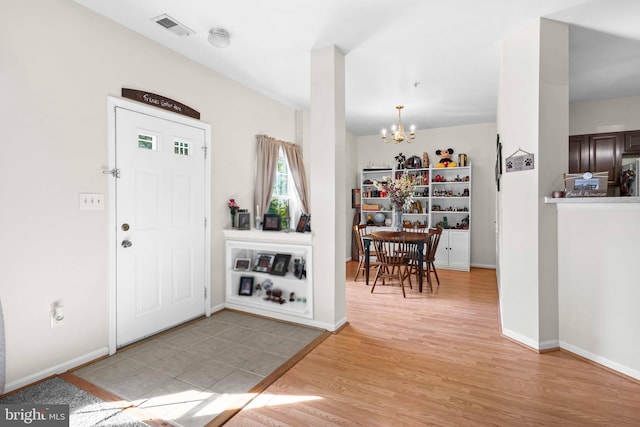 entryway with a chandelier, wood finished floors, and baseboards