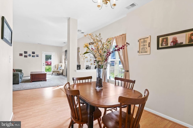 dining room featuring light wood finished floors, a chandelier, and baseboards