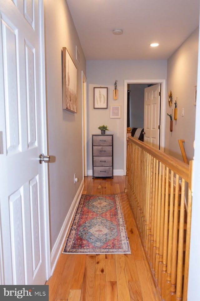 corridor with light wood-style floors, baseboards, and recessed lighting