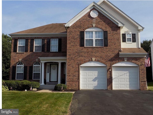 colonial inspired home with brick siding, driveway, an attached garage, a shingled roof, and a front yard