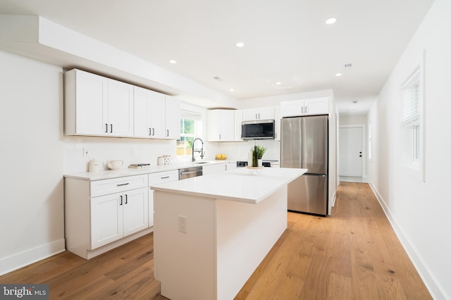 4620 Hunt Pl NE, Washington, DC 20019 - kitchen featuring stainless steel appliances, a center island, light wood finished floors, white cabinets, and tasteful backsplash
