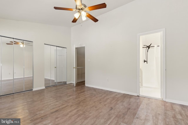 7879 Wintercress Ln, Springfield, VA 22152 - unfurnished bedroom featuring two closets, wood finished floors, high vaulted ceiling, ensuite bathroom, and baseboards