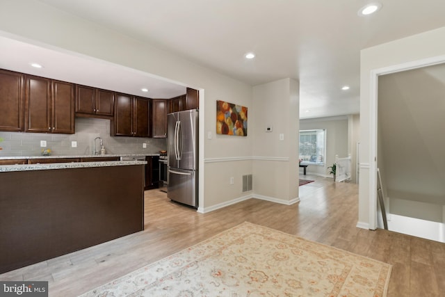 7879 Wintercress Ln, Springfield, VA 22152 - kitchen featuring freestanding refrigerator, light wood-style flooring, dark brown cabinets, a sink, and backsplash