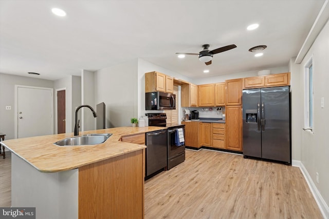 kitchen with appliances with stainless steel finishes, a sink, a peninsula, a ceiling fan, and light wood-style floors