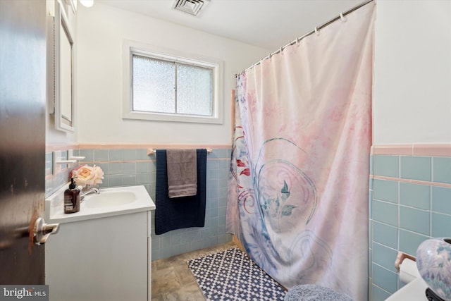 full bathroom featuring tile walls, wainscoting, vanity, and curtained shower