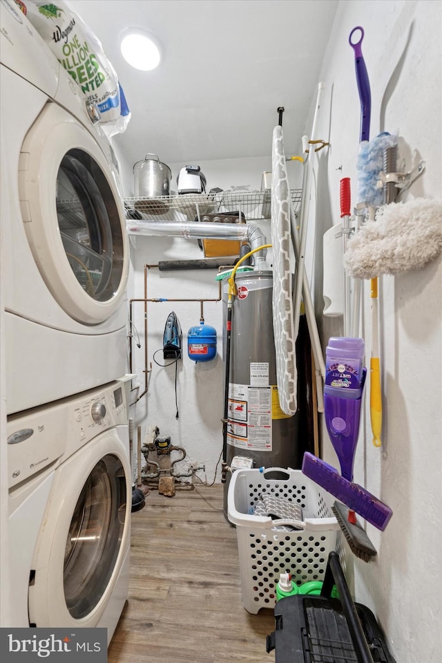laundry room featuring stacked washer / drying machine, wood finished floors, and water heater