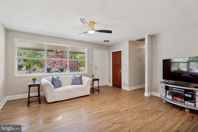 living area with wood finished floors, a ceiling fan, and baseboards