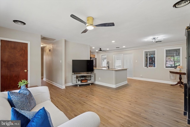 living area featuring a ceiling fan, light wood-type flooring, baseboards, and recessed lighting