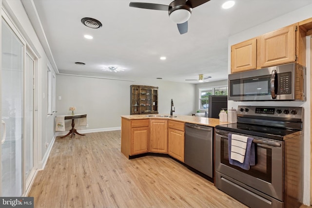 kitchen with stainless steel appliances, ceiling fan, a peninsula, light wood finished floors, and a sink