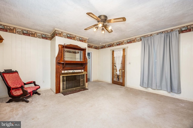 sitting room with a ceiling fan, a fireplace with flush hearth, carpet floors, and a textured ceiling