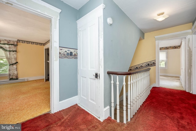 corridor with carpet flooring, baseboards, and a baseboard heating unit