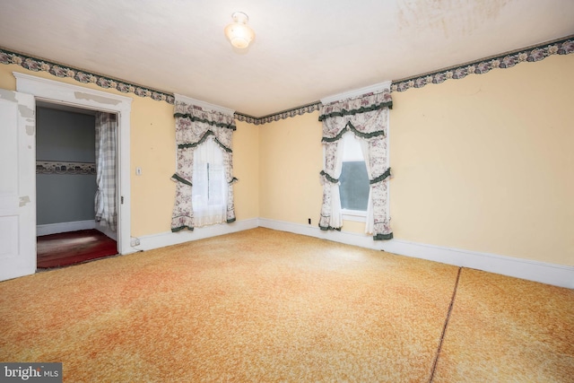 empty room featuring carpet and baseboards