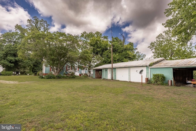 view of grassy yard featuring an outbuilding, a pole building, and a garage