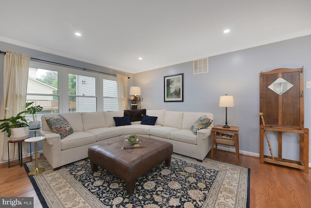 living room featuring light wood-style floors, ornamental molding, baseboards, and recessed lighting