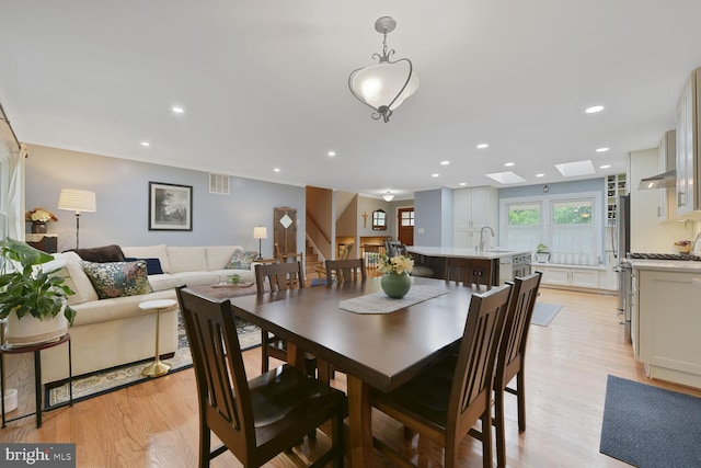 dining room featuring light wood-style floors, recessed lighting, stairway, and a skylight