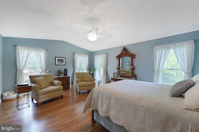 bedroom with multiple windows, vaulted ceiling, wood finished floors, and a ceiling fan