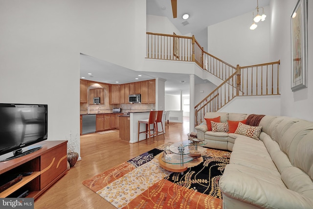 living room featuring light wood finished floors, high vaulted ceiling, and stairs