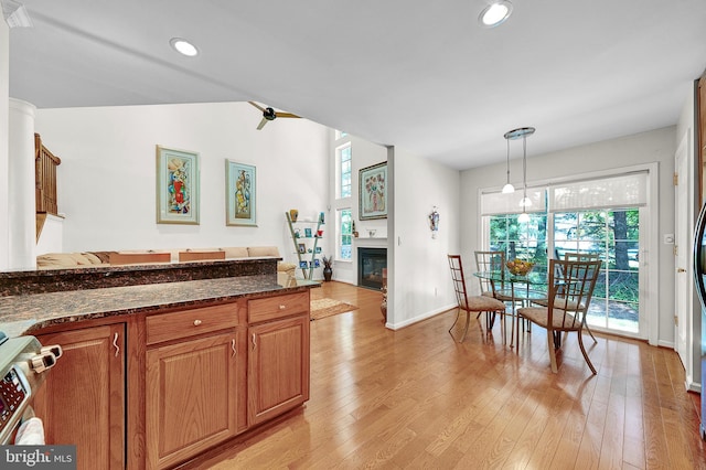 kitchen featuring light wood-style flooring, dark stone counters, baseboards, decorative light fixtures, and recessed lighting