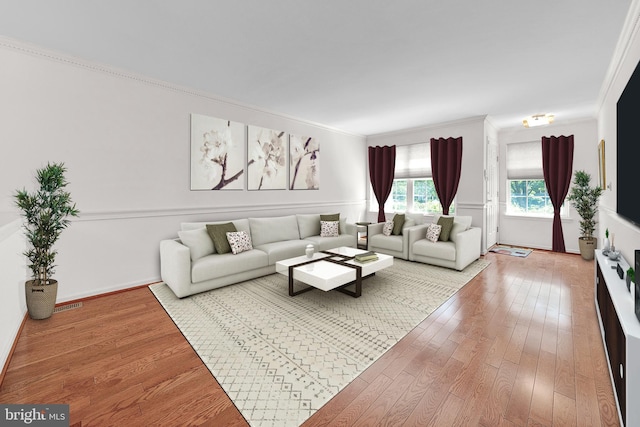 living area with crown molding, hardwood / wood-style floors, and baseboards