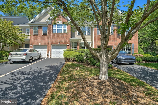 view of property with driveway, brick siding, and a garage