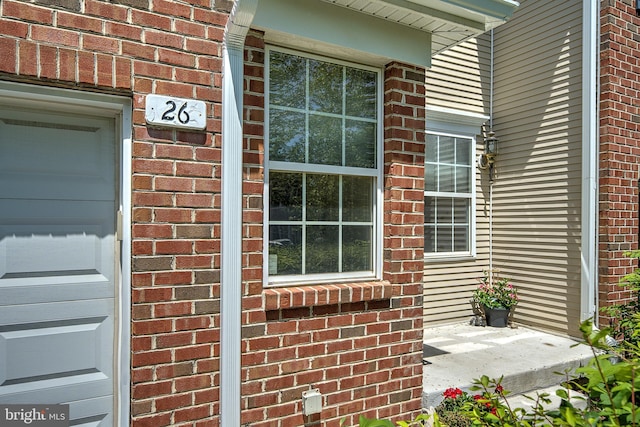 view of exterior entry featuring brick siding and covered porch