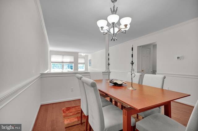 dining room with a chandelier, wood finished floors, crown molding, and baseboards