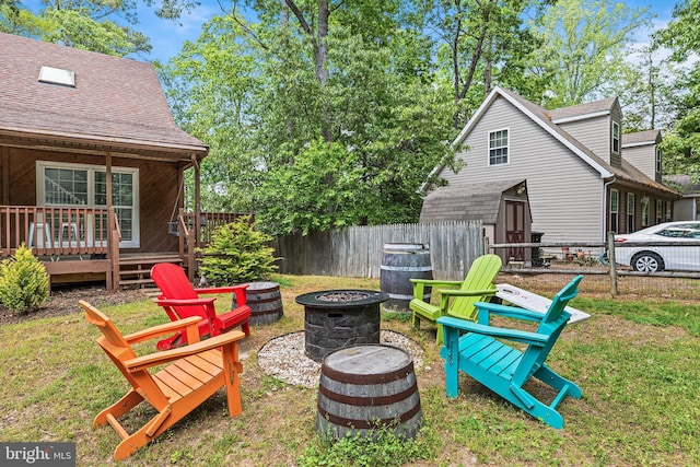 view of yard featuring an outdoor fire pit, a storage shed, a wooden deck, and an outdoor structure