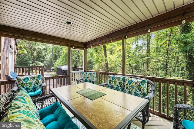 wooden deck with outdoor dining space and view of scattered trees