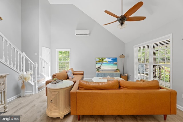 living room featuring high vaulted ceiling, stairway, light wood-type flooring, a ceiling fan, and healthy amount of natural light