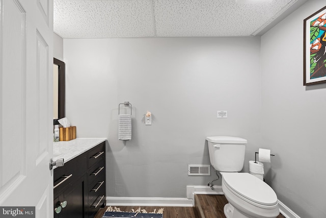 half bath featuring baseboards, wood finished floors, toilet, and vanity