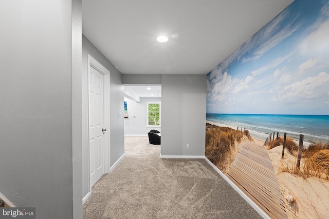 hallway featuring carpet, baseboards, view of water and beach, and recessed lighting