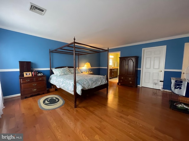 bedroom featuring wood finished floors, ornamental molding, and baseboards