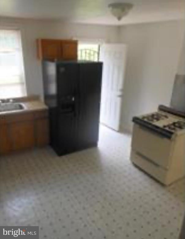 5848 Morton St, Philadelphia, PA 19144 - kitchen featuring black fridge, a sink, and brown cabinetry