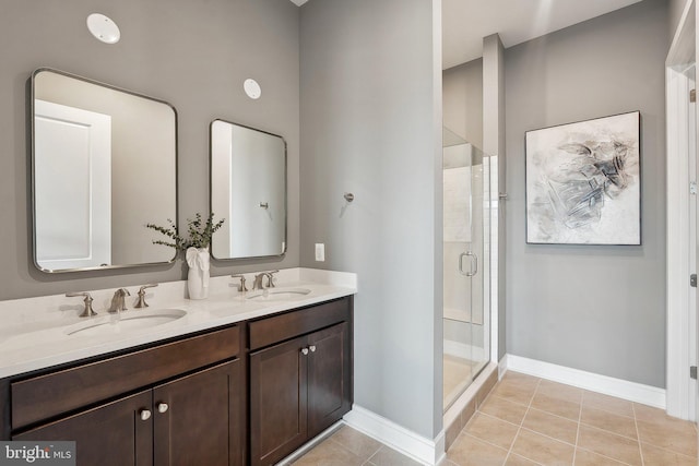 full bathroom featuring tile patterned floors, a shower stall, double vanity, and baseboards