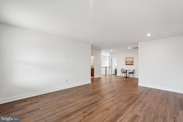 unfurnished living room with wood finished floors, recessed lighting, and baseboards