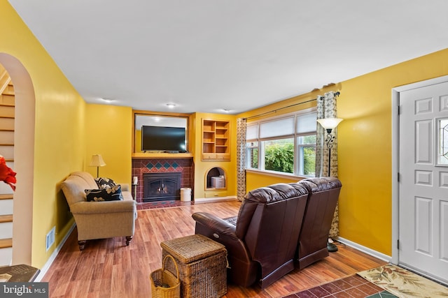 115 Diller Rd, New Cumberland, PA 17070 - living room featuring wood finished floors, a brick fireplace, arched walkways, and baseboards